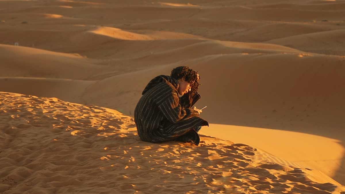 Symbolfoto: Junger Mann mit Telefon in der Wüste
